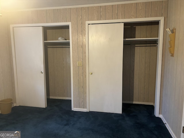 unfurnished bedroom with wooden walls and dark colored carpet