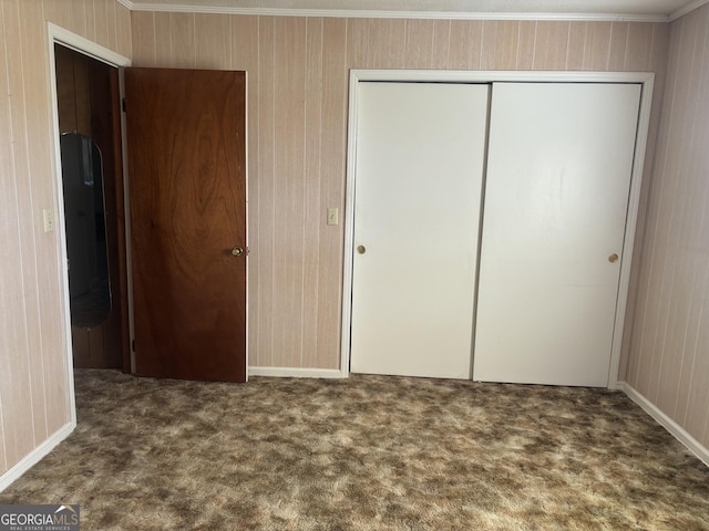 unfurnished bedroom with crown molding, dark carpet, and a closet