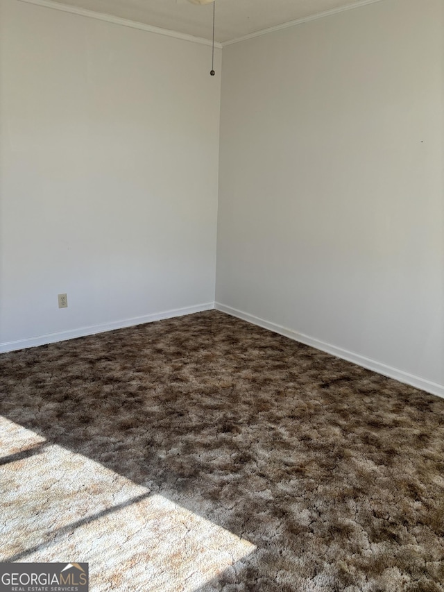 spare room with ornamental molding, dark carpet, and baseboards