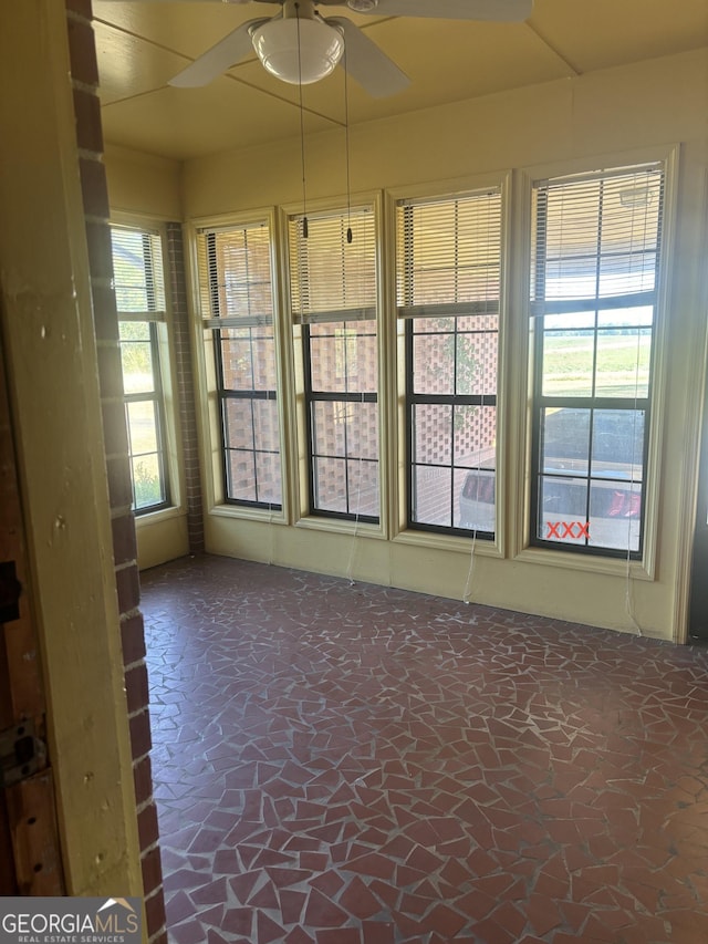 unfurnished sunroom with a ceiling fan