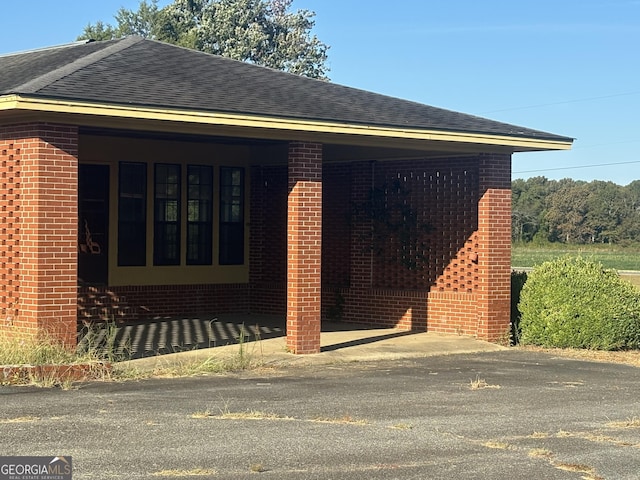 view of side of home featuring a shingled roof and brick siding