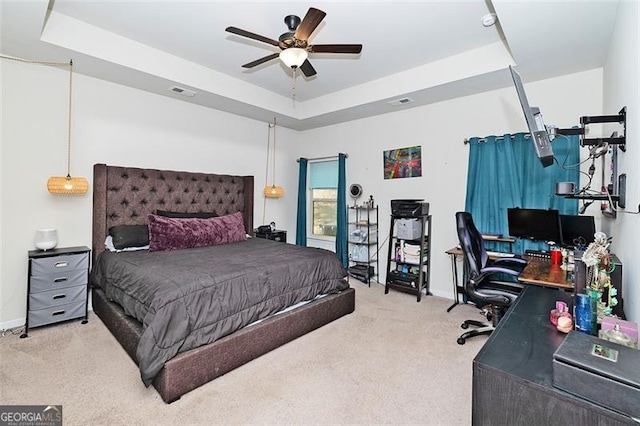 bedroom with visible vents, a tray ceiling, a ceiling fan, and light colored carpet