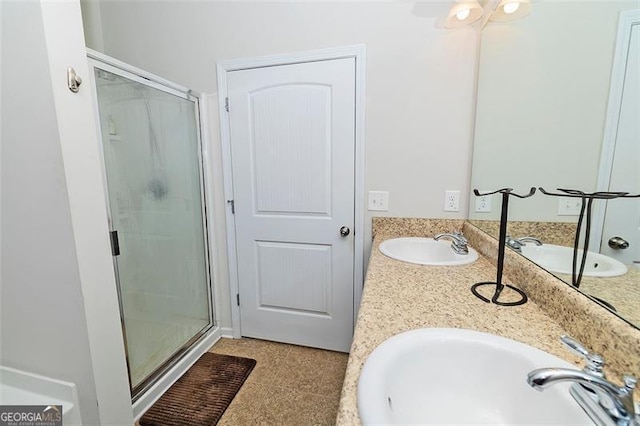 full bathroom with double vanity, a shower stall, and a sink