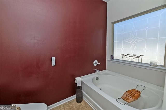 bathroom with a garden tub and baseboards