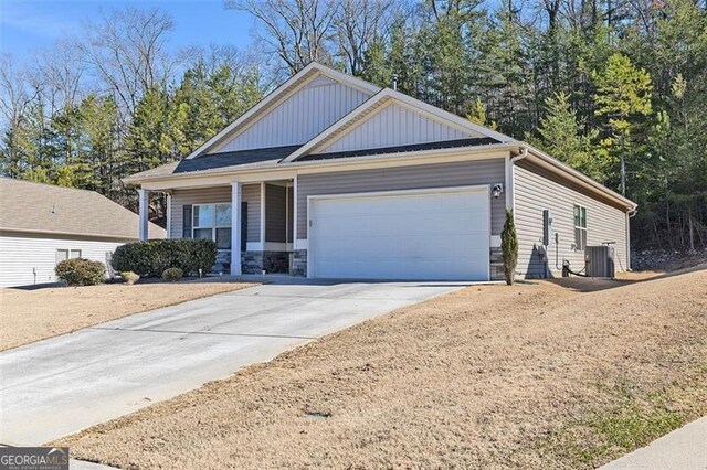 view of front of property with central air condition unit, board and batten siding, a garage, stone siding, and driveway