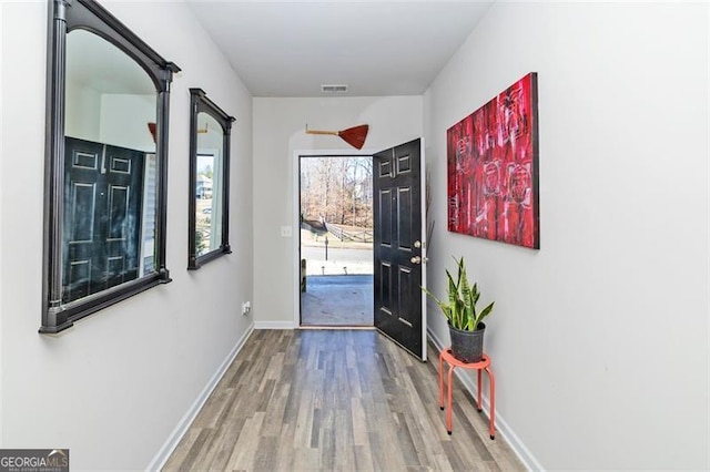 entryway with wood finished floors, visible vents, and baseboards