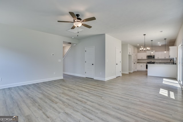 unfurnished living room with recessed lighting, ceiling fan with notable chandelier, a sink, baseboards, and light wood-style floors