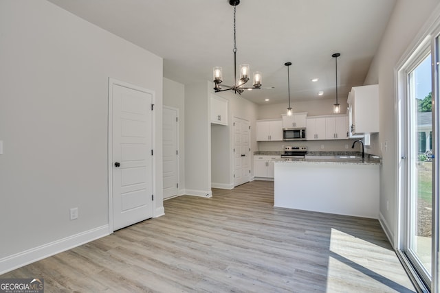 kitchen featuring light stone counters, stainless steel appliances, light wood-style flooring, white cabinets, and a sink