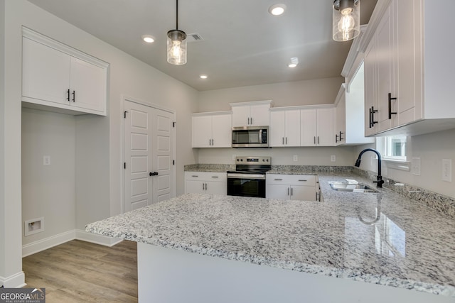 kitchen with visible vents, white cabinets, appliances with stainless steel finishes, a peninsula, and a sink