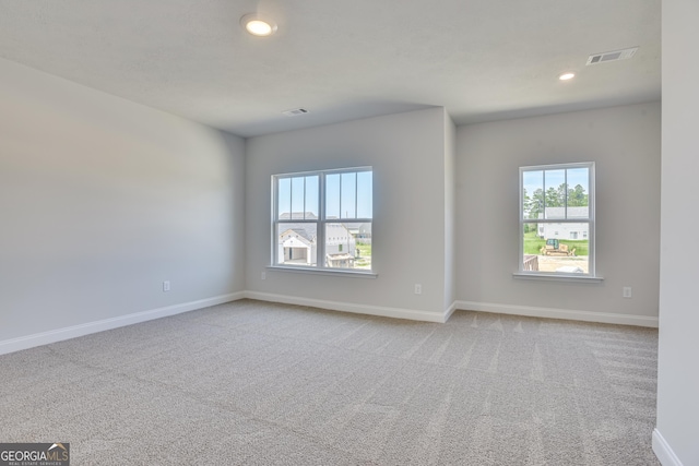 carpeted spare room featuring recessed lighting, visible vents, and baseboards