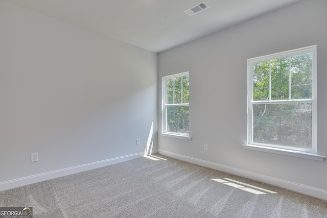 carpeted spare room featuring visible vents and baseboards