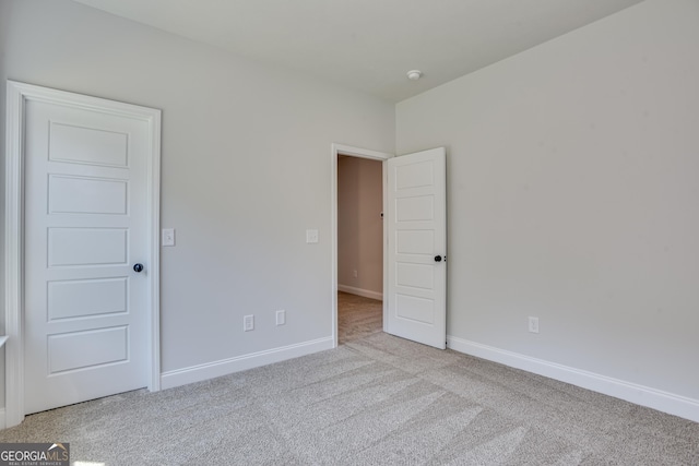 unfurnished bedroom featuring light carpet and baseboards