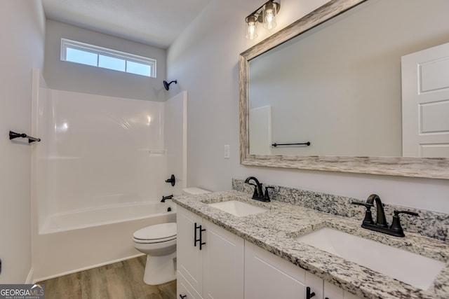 bathroom featuring toilet, a sink, shower / tub combination, and wood finished floors