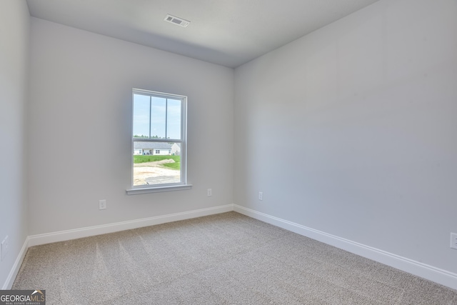 carpeted spare room with visible vents and baseboards