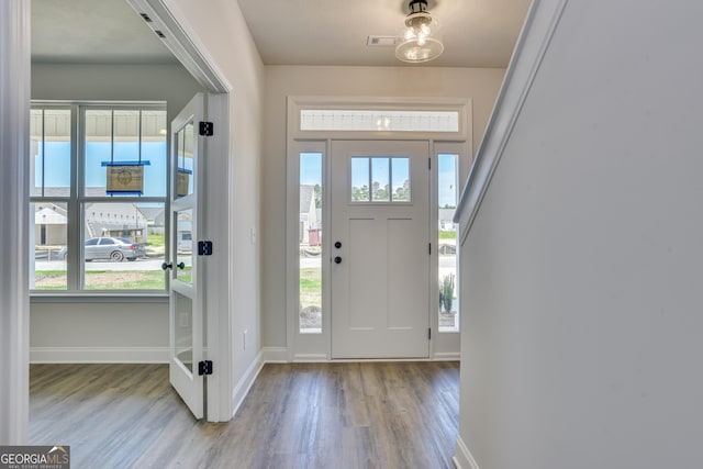 foyer entrance featuring baseboards, light wood finished floors, visible vents, and a healthy amount of sunlight