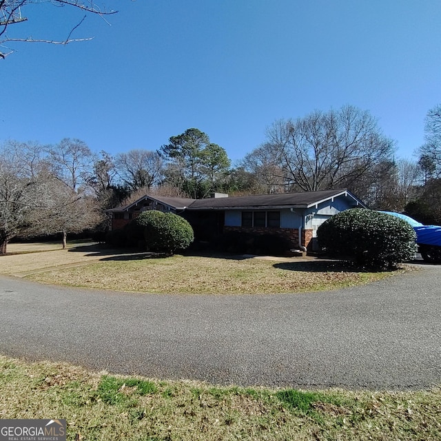 view of front of house featuring a garage, aphalt driveway, and a front lawn