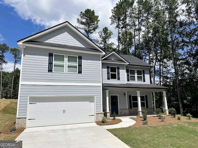 view of front of home featuring a garage, covered porch, driveway, and a front lawn