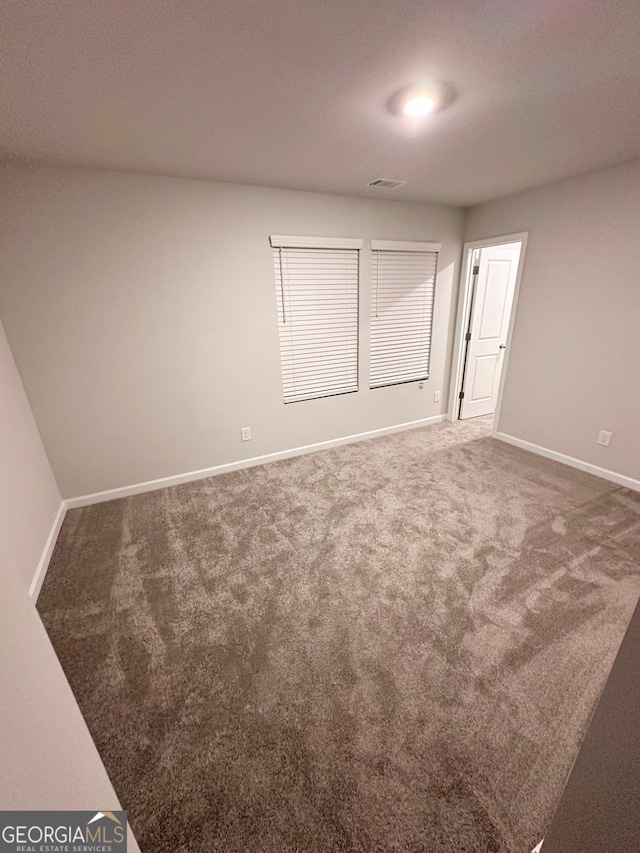 carpeted spare room with visible vents and baseboards