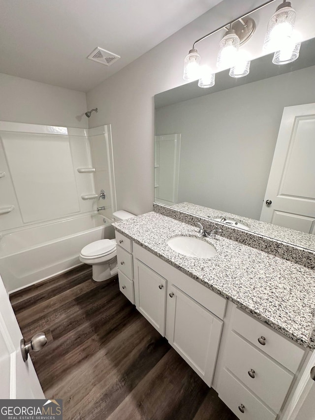 full bathroom featuring toilet, wood finished floors, vanity, visible vents, and shower / washtub combination