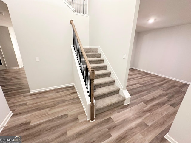 stairway with baseboards, wood finished floors, and recessed lighting