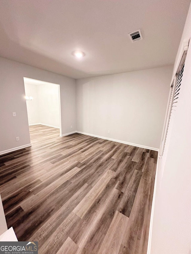 spare room with baseboards, visible vents, and wood finished floors