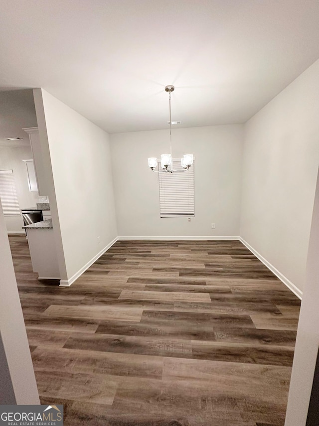 unfurnished dining area with baseboards, a chandelier, and dark wood-type flooring