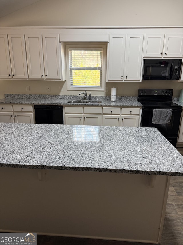 kitchen with light stone countertops, black appliances, and a sink