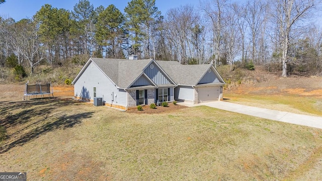 view of front of house with driveway, a trampoline, a front lawn, board and batten siding, and brick siding