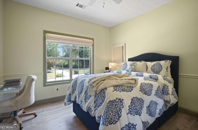 bedroom with ceiling fan, wood finished floors, visible vents, and baseboards