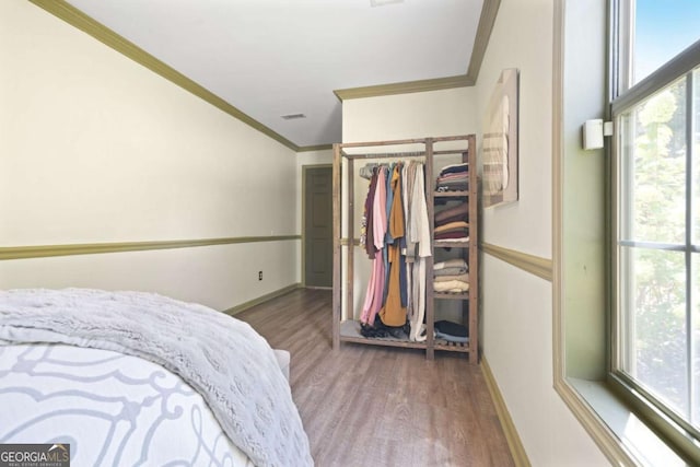 bedroom with baseboards, visible vents, ornamental molding, and wood finished floors