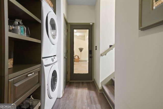 laundry area featuring stacked washer and dryer, dark wood finished floors, and cabinet space