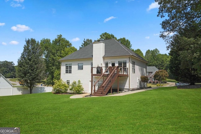 rear view of property with stairway, a wooden deck, a lawn, and fence