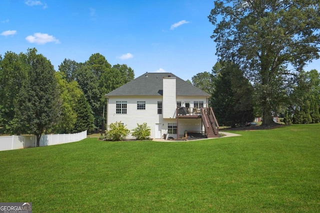 rear view of property featuring a deck, fence, stairway, a lawn, and a chimney