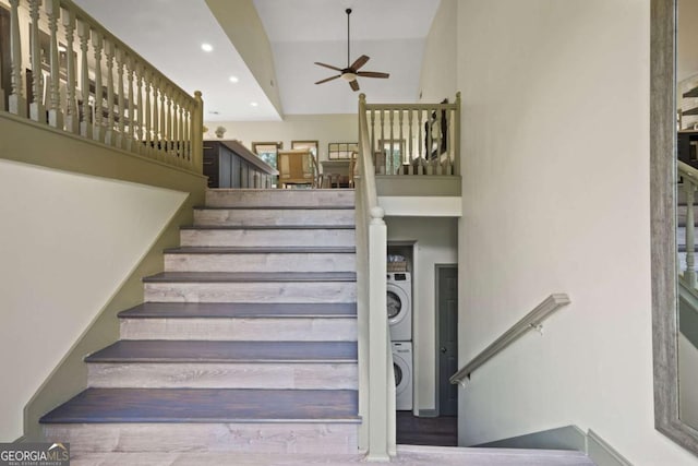 stairway featuring a ceiling fan, stacked washer / dryer, a towering ceiling, and recessed lighting