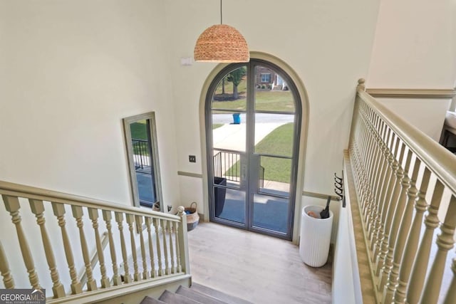 foyer featuring french doors, a high ceiling, stairway, and light wood finished floors