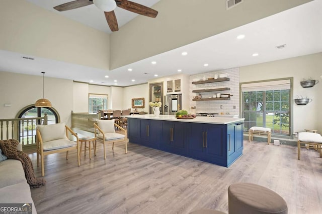 kitchen featuring blue cabinets, hanging light fixtures, light countertops, stainless steel refrigerator with ice dispenser, and open shelves