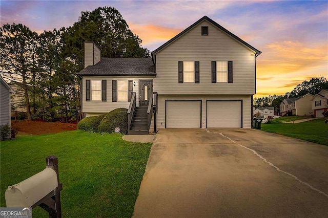 tri-level home with driveway, a garage, a chimney, and a front lawn