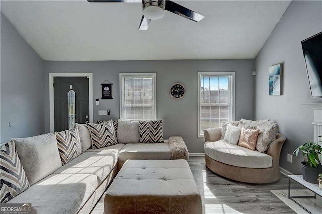 living area featuring lofted ceiling, ceiling fan, light wood-style flooring, and baseboards