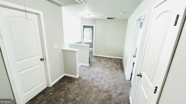 hallway featuring visible vents, baseboards, an upstairs landing, dark carpet, and attic access