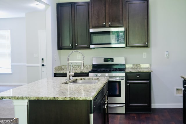 kitchen with appliances with stainless steel finishes, a sink, and a kitchen island with sink