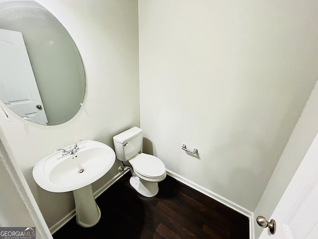 half bathroom featuring baseboards, toilet, and wood finished floors