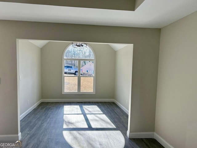 unfurnished room featuring dark wood-type flooring, vaulted ceiling, and baseboards