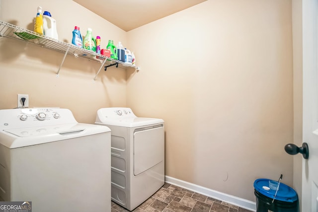 laundry area featuring laundry area, stone finish flooring, baseboards, and washing machine and clothes dryer