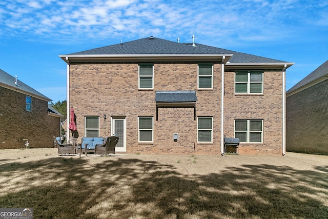 rear view of house with a yard, a patio, and brick siding