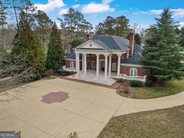 greek revival house with covered porch, roof with shingles, and a chimney