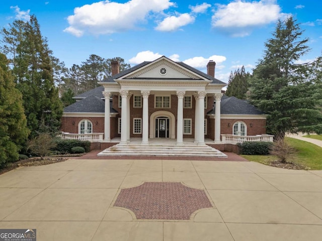 view of front of property featuring driveway, a chimney, and brick siding