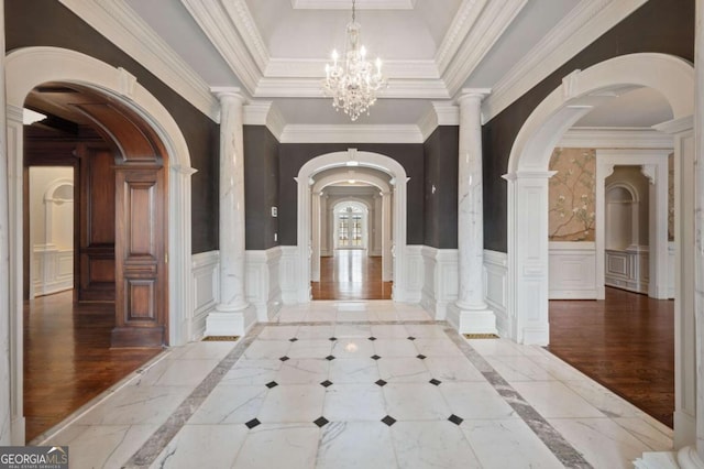 entryway featuring a chandelier, wood finished floors, wainscoting, and a raised ceiling