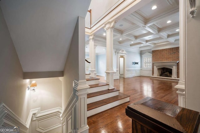 interior space featuring a large fireplace, coffered ceiling, beam ceiling, ornate columns, and crown molding