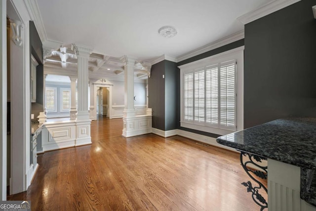 dining room with decorative columns, ornamental molding, coffered ceiling, and wood finished floors