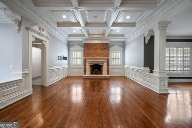 unfurnished living room with beamed ceiling, a brick fireplace, dark wood finished floors, and ornate columns